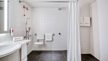 Un baño moderno con ducha, inodoro y lavamanos. Hay toallas colgadas en la pared y una cortina de ducha.