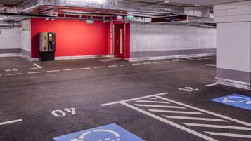 Eine Parkgarage mit ausgewiesenen Behindertenparkplätzen, einer roten Wand und einem Aufzug.