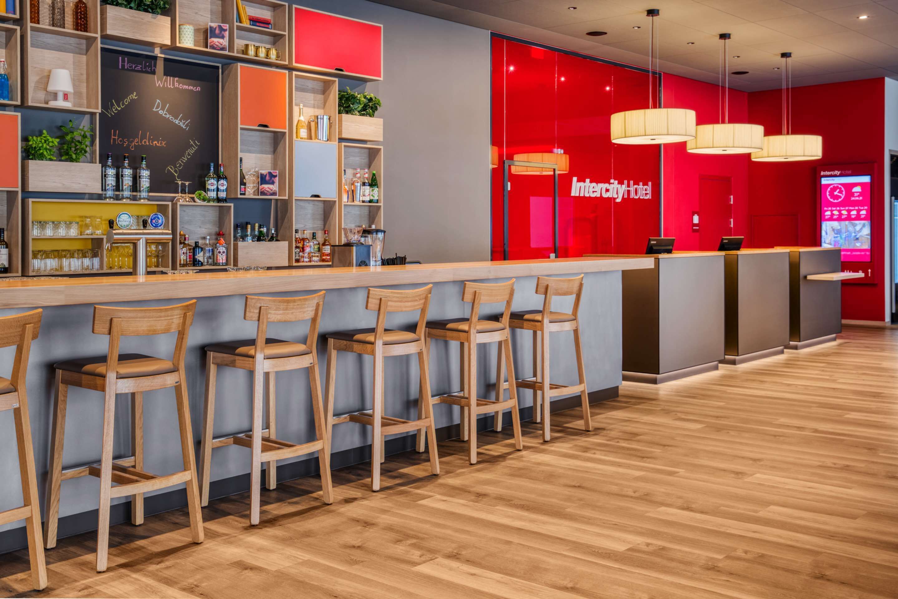 A modern bar area with wooden bar stools and a red accent wall.