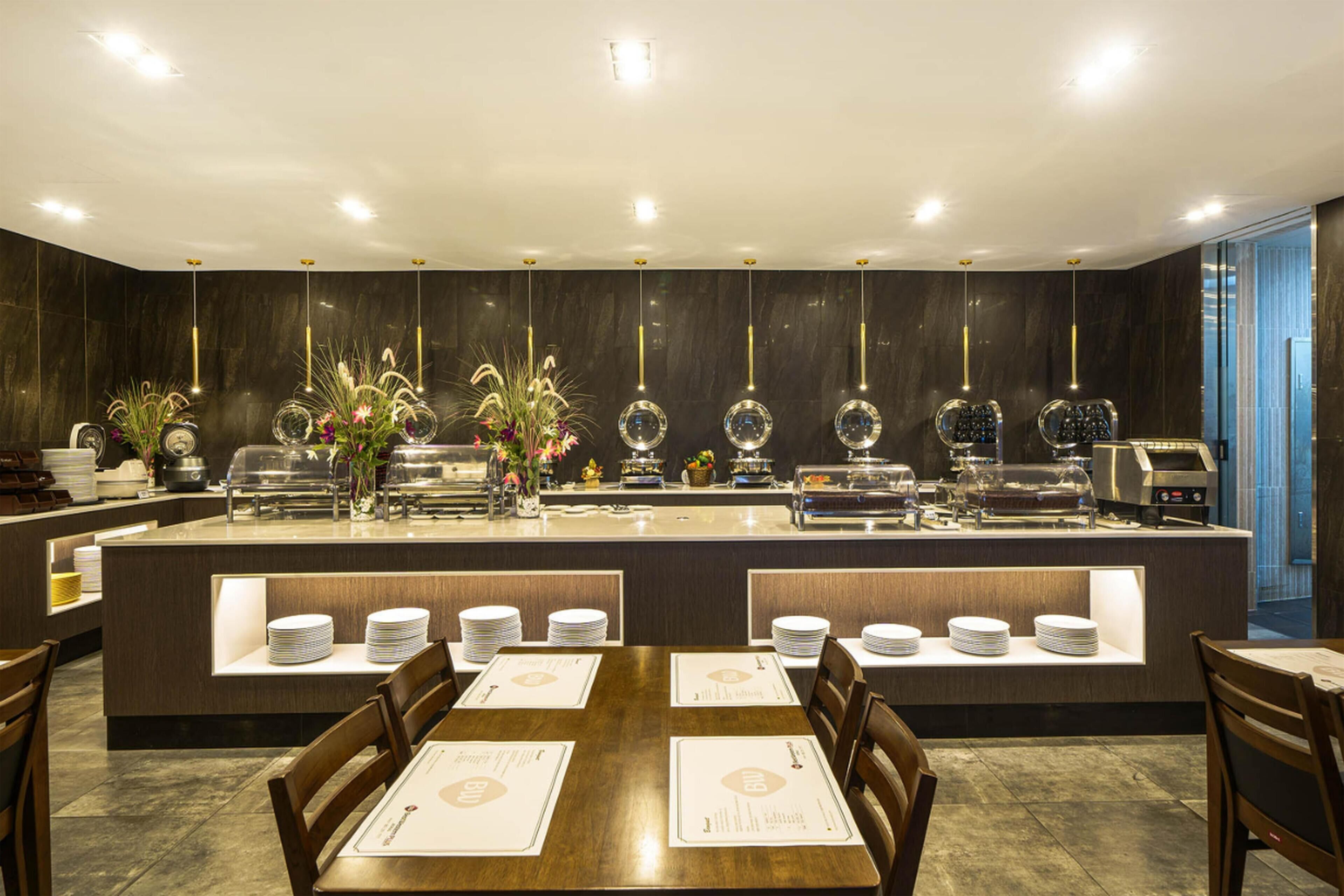 Un restaurant doté d’un long comptoir, de plusieurs postes de service et d’un espace où les clients peuvent s’asseoir à des tables et sur des chaises.