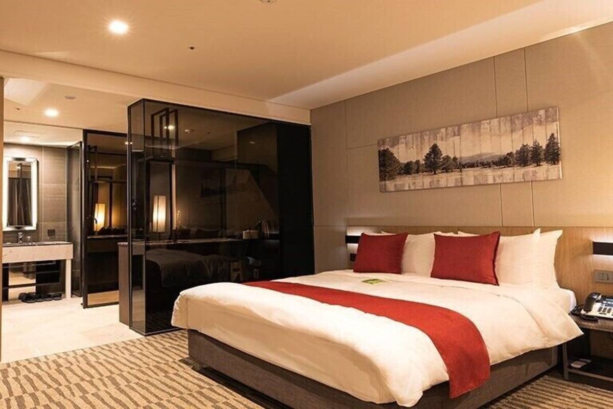 Ein Hotelzimmer mit einem großen Bett, einem Schreibtisch mit Stuhl, einem Spiegel und einem Bild an der Wand.