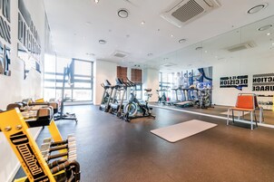 A gym with exercise equipment, large windows, and a mirror wall.