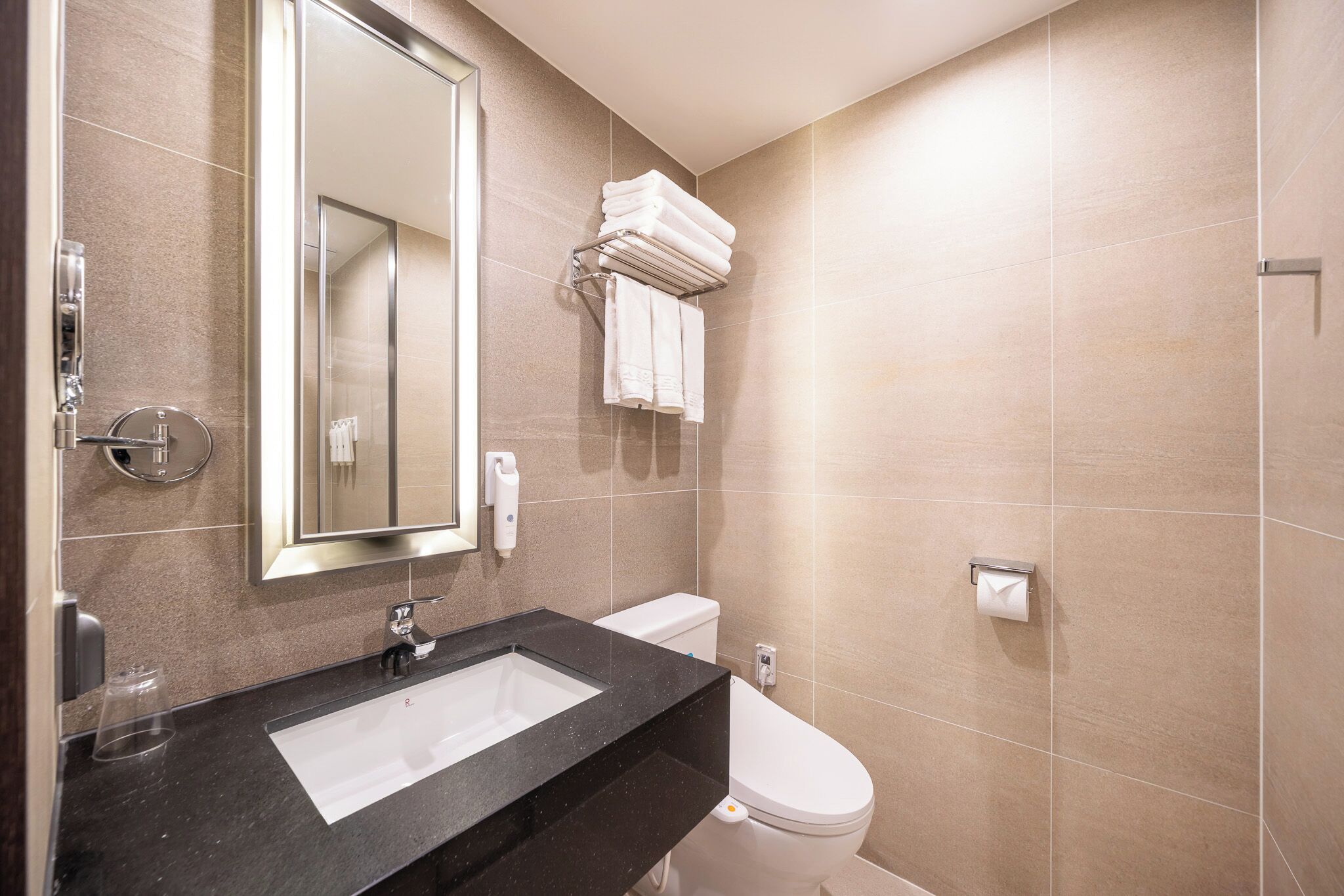 A modern bathroom with a black sink, a toilet, and a towel rack.
