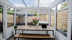 A conservatory with a wooden table, a laptop, and a vase of flowers. - Luxury Townhouse with Hot tub & Parking* Special offer 20% off August dates* (St Andrews)