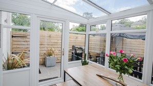 A conservatory with a wooden table and chairs, a grill, and a potted plant. - Luxury Townhouse with Hot tub & Parking* Special offer 20% off August dates* (St Andrews)