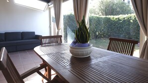 A dining area with a wooden table and chairs, a potted plant, and a sofa. - Aria di Vacanza - Capo Ceraso Bunte (Olbia)