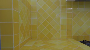 A bathroom with yellow tiled walls and floor, featuring a geometric pattern. - Aria di Vacanza - Capo Ceraso Bunte (Olbia)