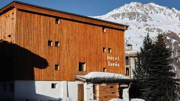 A wooden building with the sign "hôtel los lórés" and a mountain in the background.