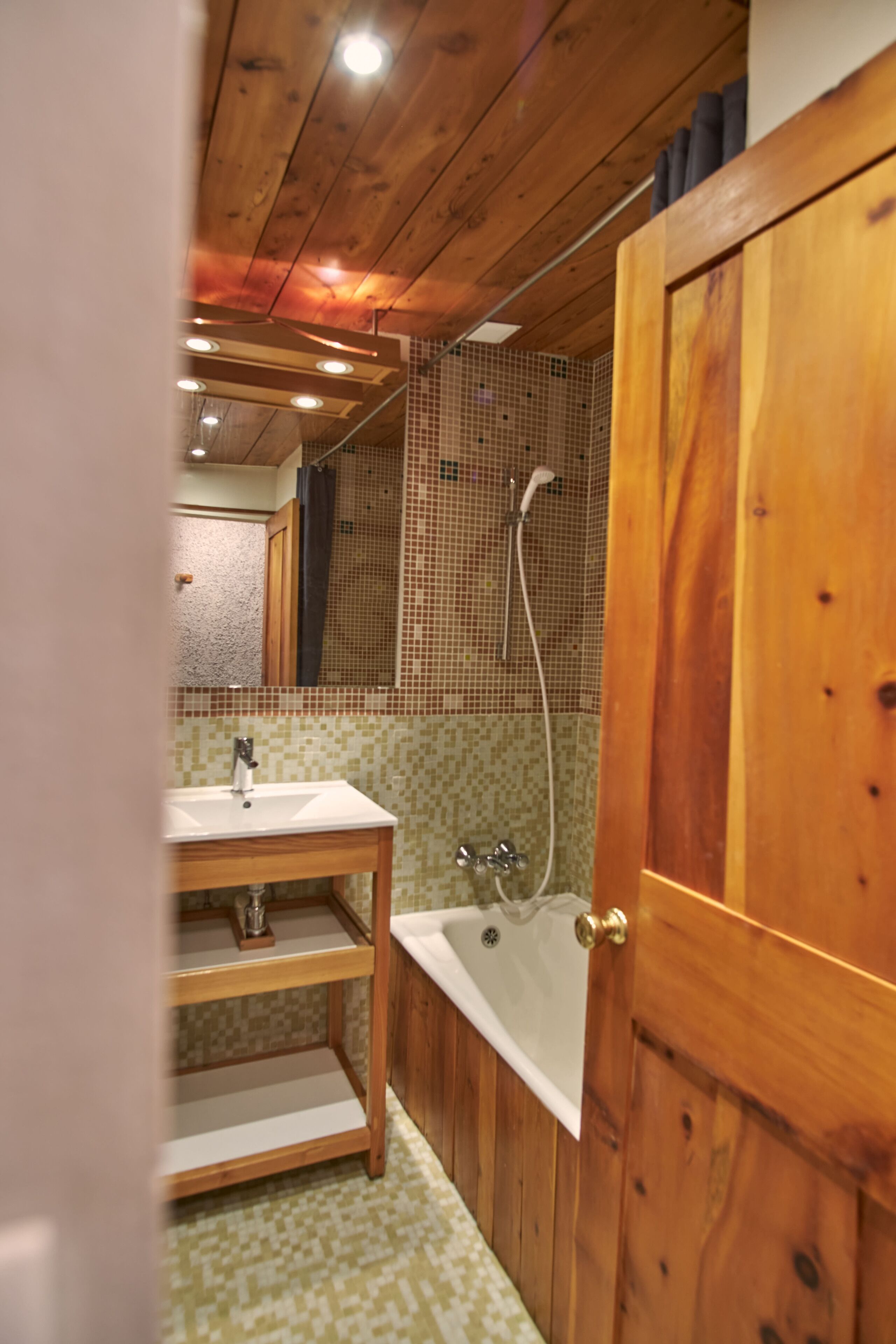 A wooden-paneled bathroom with a sink, vanity, and bathtub.