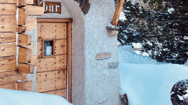 A wooden building with a sign reading "restaurant la charpenterie" and a door labeled "bar". - Hôtel les Lorès (Val-d'Isere)