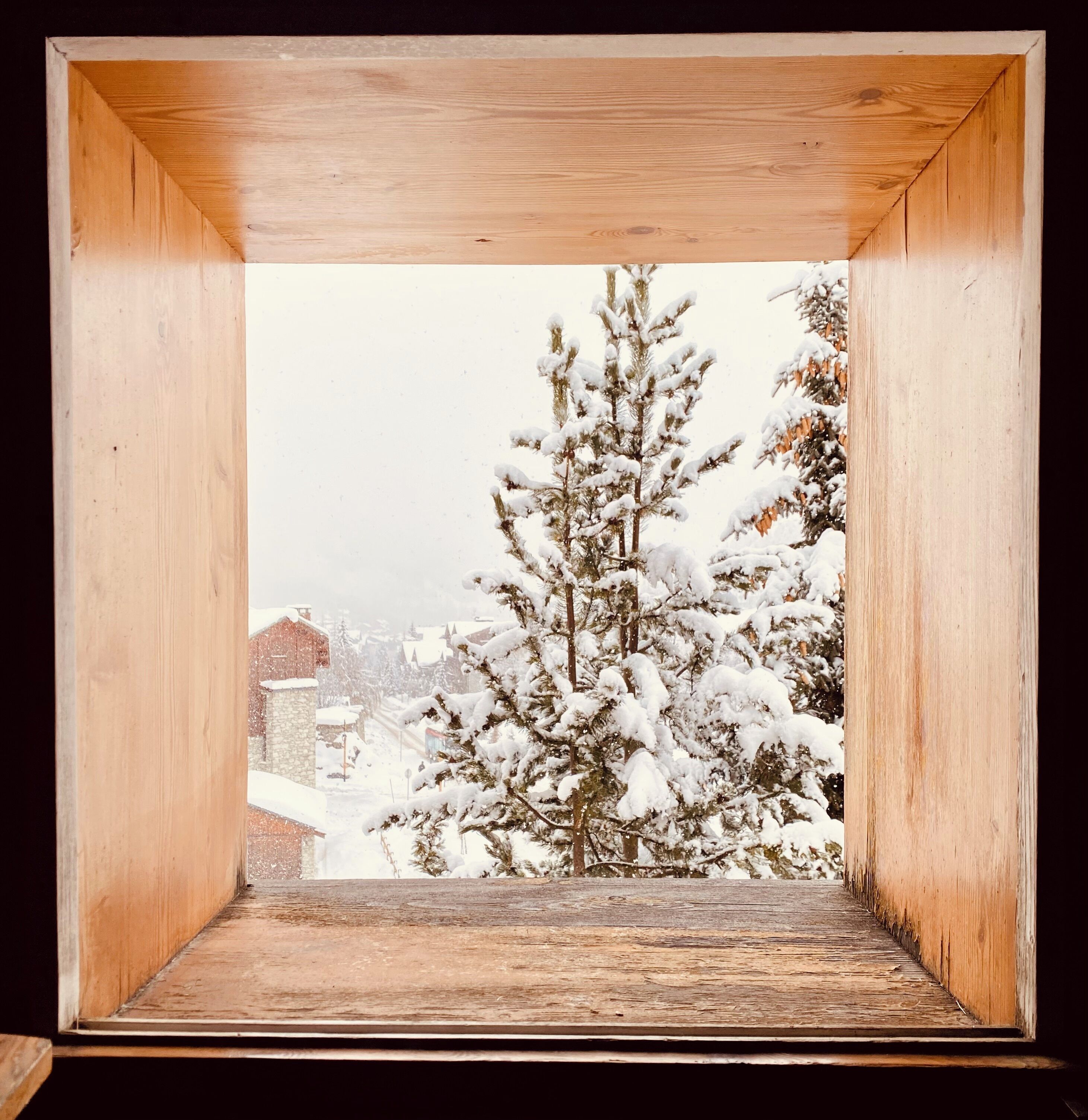 A wooden box with a snowy landscape view, including snow-covered trees and buildings.