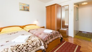 Un dormitorio con dos camas, un armario, un espejo y una puerta que da a otra habitación.