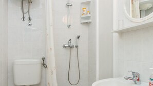 Un baño con inodoro, ducha, lavabo y espejo.