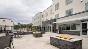 Un espace extérieur aménagé en terrasse, avec des jardinières en pierre, des sièges et un foyer.