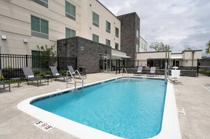 A swimming pool with lounge chairs and a building with a stone facade.