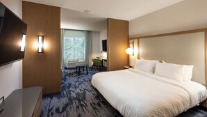 Une chambre d’hôtel avec un grand lit, un bureau, une chaise et un téléviseur.