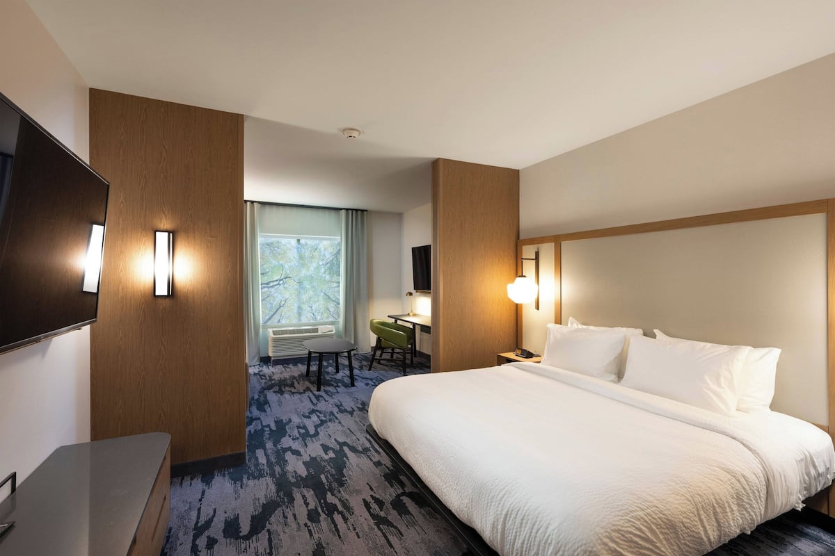 Una habitación de hotel con una cama grande, un escritorio, una silla y un televisor.