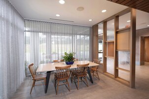A dining area with a large table, wooden chairs, a blue bowl with plants, and frosted glass panels.