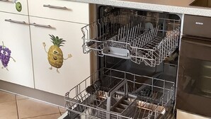 An open dishwasher with multiple racks and a control panel. - Haus Ruhland (Tiefenbach)