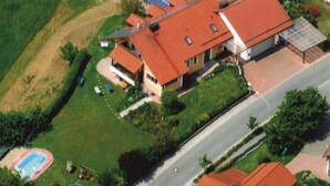 A house with a red roof, solar panels, a swimming pool, and a well-maintained lawn. - Haus Ruhland (Tiefenbach)
