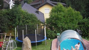 A backyard with a trampoline, a small pool slide, and a large rock. - Haus Ruhland (Tiefenbach)