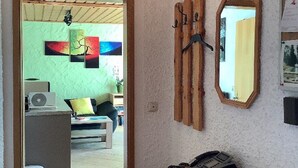A room with a wooden ceiling, a wooden cabinet, a mirror, and a door leading to another room with a green wall and a bed. - Haus Ruhland (Tiefenbach)