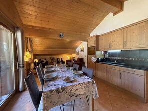 A dining area with a table set for four, wooden cabinets, and a kitchen area with a black countertop.