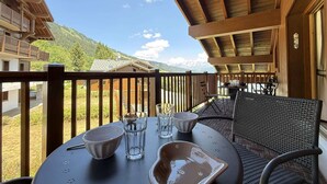 Un balcon avec une table dressée pour deux personnes, offrant une vue sur un paysage montagneux.