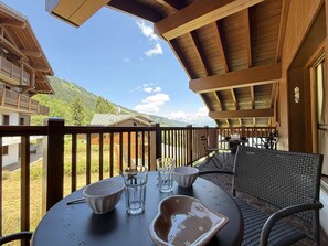 Un balcone con un tavolo apparecchiato per due, vista su un paesaggio montano.