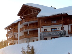 Un edificio in legno su più piani con balconi e una base in pietra, circondato dalla neve.