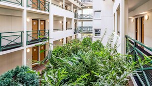 A multi-level hotel with balconies, indoor plants, and a central courtyard.