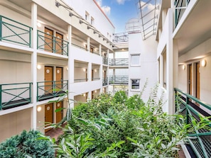 Un hôtel à plusieurs étages doté de balcons, de plantes d’intérieur et d’une cour intérieure.