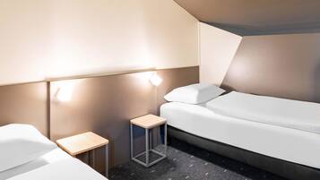 A modern hotel room with a bed, a small bedside table, and a lamp.