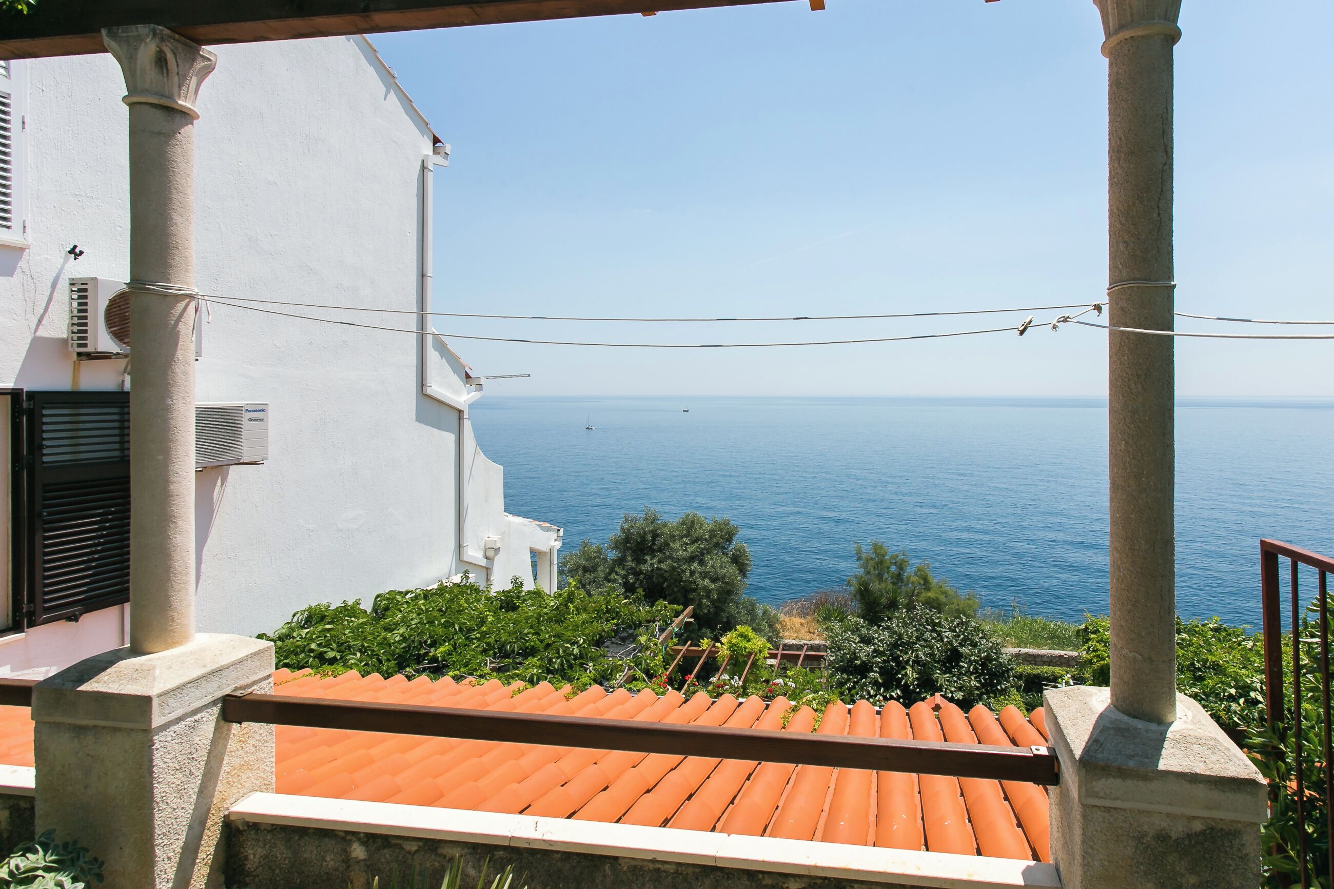 A terrace with a red-tiled roof overlooking a body of water.