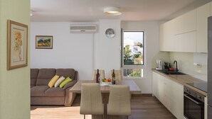 Eine moderne Küche mit Essbereich, einer Couch und Blick ins Freie.