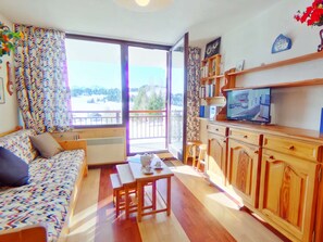 A cozy living room with a sofa, a dining table, and a TV. There's a balcony with a view of the outdoors. - 2-room apartment for 4 in Les Saisies, comfort and stunning view (Les Saisies)