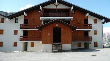 Un bâtiment à deux étages, doté d’une façade en bois, de balcons et d’une entrée centrale.