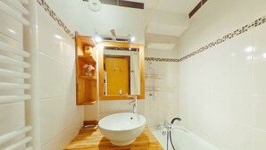 Ein Badezimmer mit einem Holzkosmetikschrank, einem weißen Waschbecken und einer Badewanne.