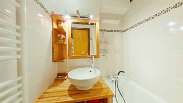 Une salle de bain avec un meuble-lavabo en bois, un lavabo blanc et une baignoire.