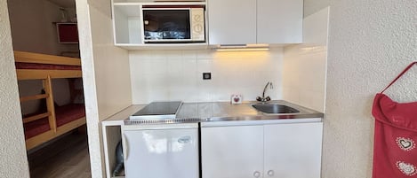 A compact kitchenette with a microwave, a small refrigerator, and a sink.