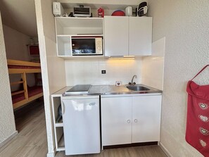 A compact kitchenette with a microwave, a small refrigerator, and a sink.