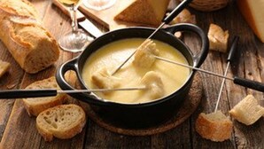 Une fondue au fromage, accompagnée de pain et de verres à vin.