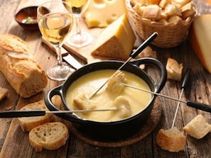 Une fondue au fromage, accompagnée de pain et de verres à vin.