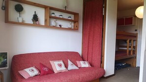 Une pièce chaleureuse avec un canapé rouge, un banc en bois et un lit superposé.