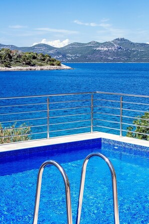 A swimming pool with metal railings, clear blue water, and a view of the sea and distant mountains. - Holiday Home Malinina (Zadar)