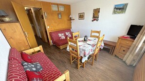 A compact room with a bed, a dining table with chairs, a small desk, and a television. - Bright studio cabin in Les Saisies, 4 ppl, south balcony (Les Saisies)