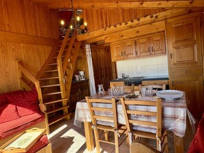A wooden cabin interior with a dining area, kitchen, and a staircase. - 2-room apartment Les Saisies, top of resort, 6 people, balcony. (Les Saisies)