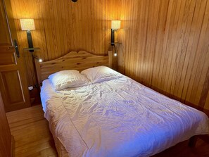 A wooden-paneled room with a bed, two wall-mounted lamps, and a door. - 2-room apartment Les Saisies, top of resort, 6 people, balcony. (Les Saisies)