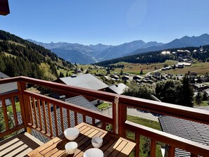 A wooden deck with a view of a mountain village and surrounding hills. - 2-room apartment Les Saisies, top of resort, 6 people, balcony. (Les Saisies)