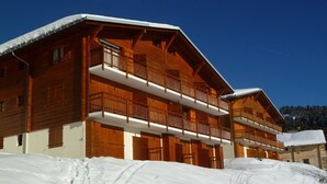 A wooden chalet with multiple balconies, set against a snowy backdrop. - 2-room apartment Les Saisies, top of resort, 6 people, balcony. (Les Saisies)